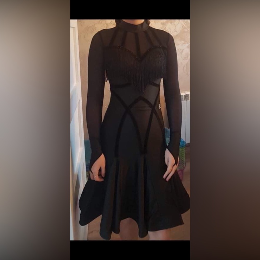 Black dress for dancing has body build, long sleeves, shinny appliqué and frills